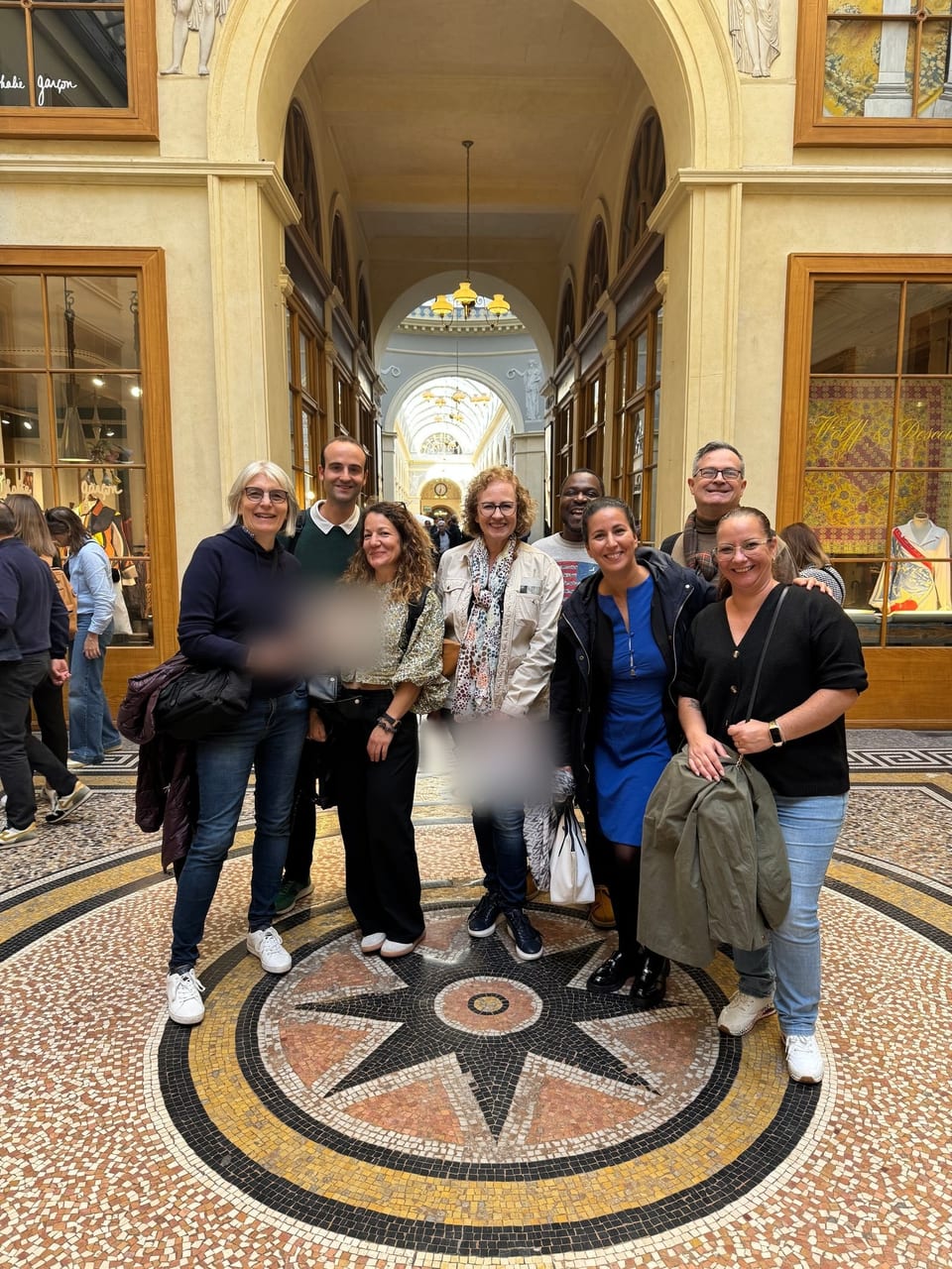 Un groupe de team-building souriant, réuni sur la mosaïque de la galerie Vivienne